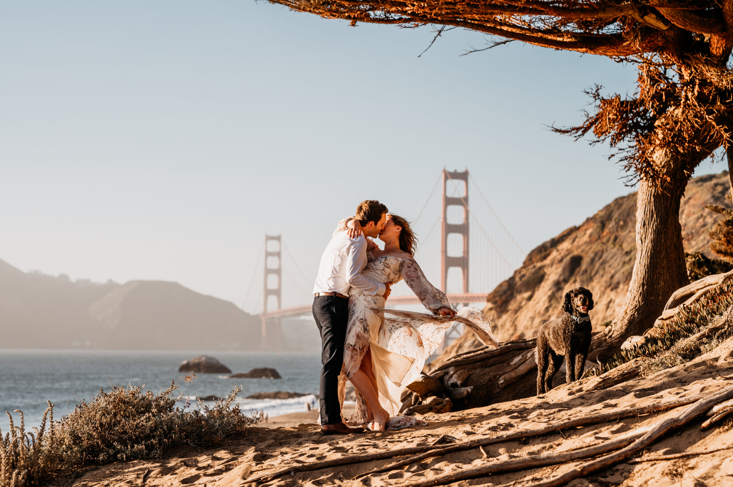 A couple in front of the Golden Gate Bridge in San Francisco celebrating their sunset elopement with their dog.