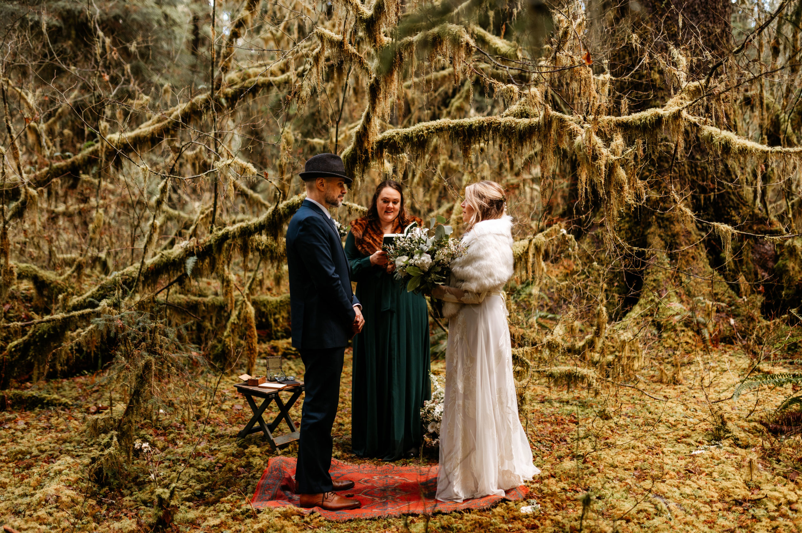 A bride and groom have a wedding ceremony in a mossy rainforest within Olympic National Park for their elopement wedding.