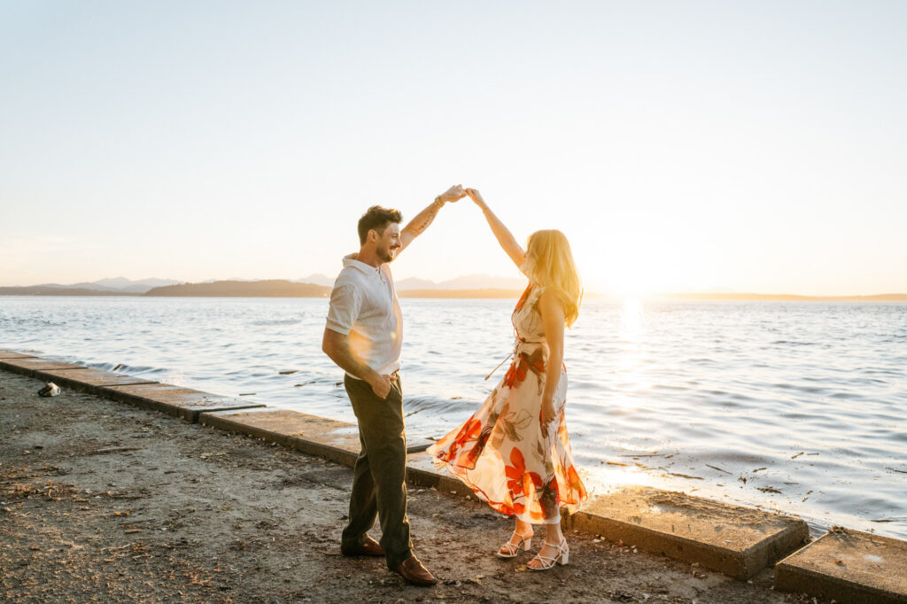 Couple dances together for their engagement photos at Alki Beach in Seattle