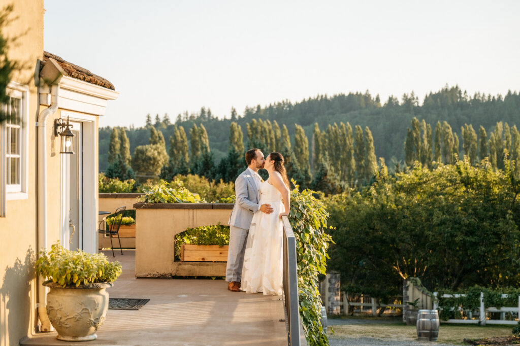 Couple shares romantic kiss in front of the sunset at a Paciic Northwest wedding venue.